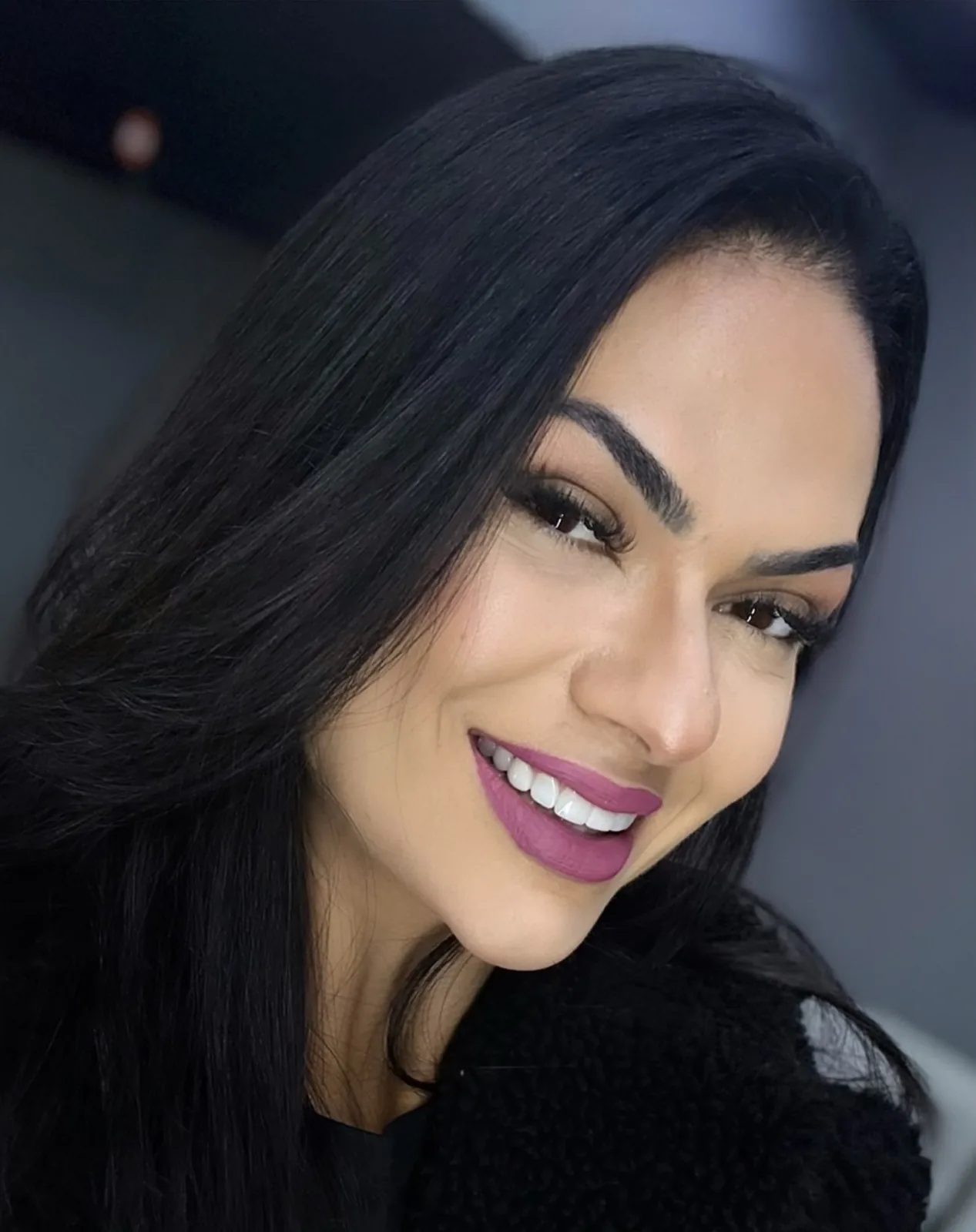 Beatriz Faria em retrato de perto, sorrindo, de cabelo preto solto