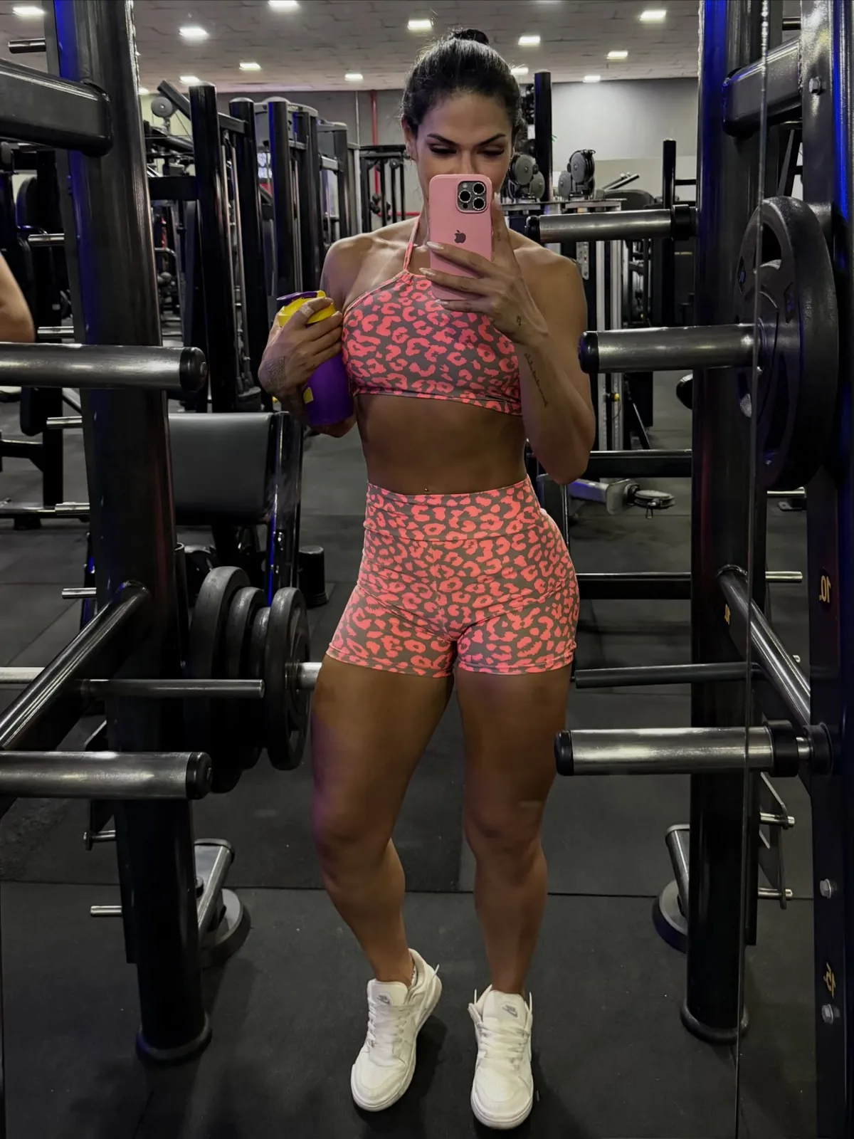 Beatriz Faria tirando selfie no espelho da academia, de conjunto rosa estampado